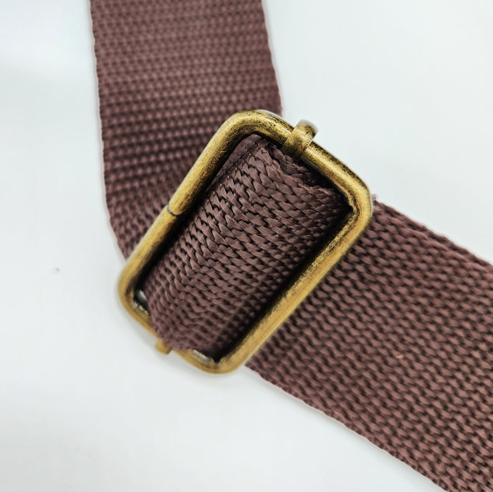 A close up image of the hardware used to adjust the Stella Bag Strap. a brass adjuster is used on brown strapping.